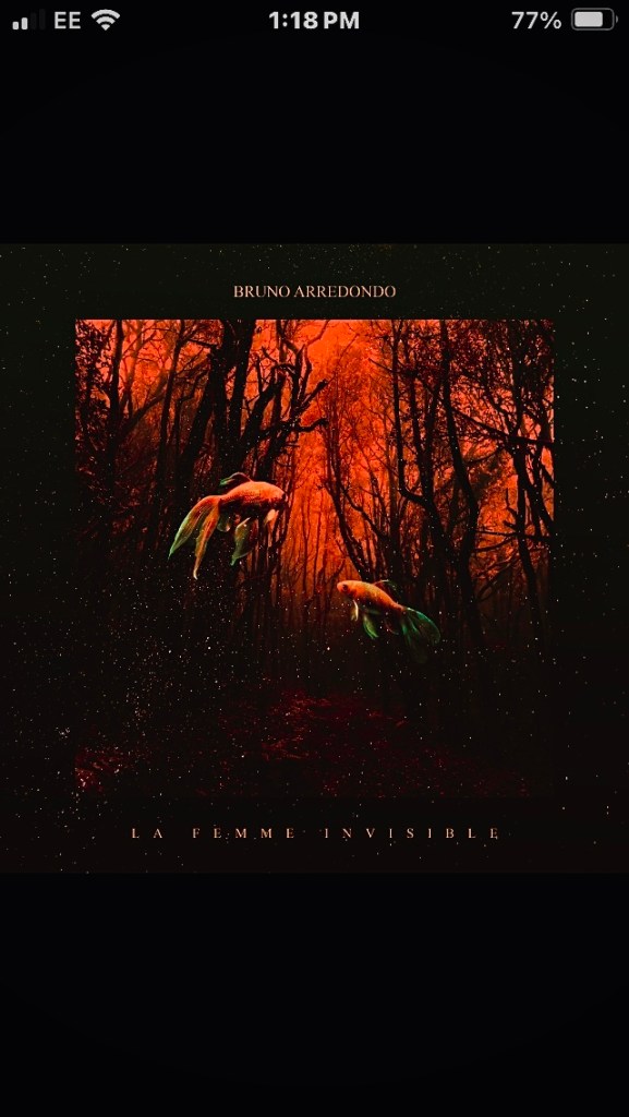 Portada del álbum 'La Femme Invisible' de Bruno Arredondo, con un fondo oscuro y un paisaje forestal en tonos rojos, donde hay dos peces con aletas coloridas flotando.